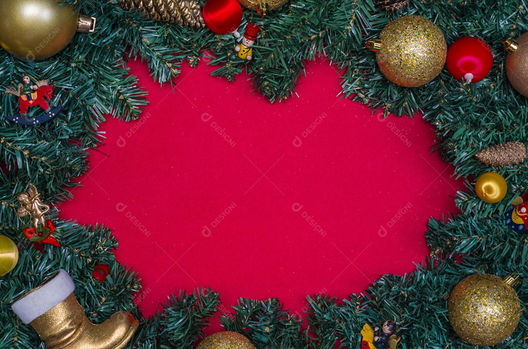 Fundo com tema natalino, folhas de pinheiro nas bordas de papel vermelho e objetos decorativos.