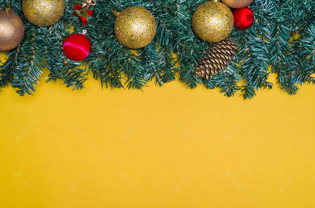Textura com tema de Natal com folhas verdes, objetos decorativos e fundo amarelo.