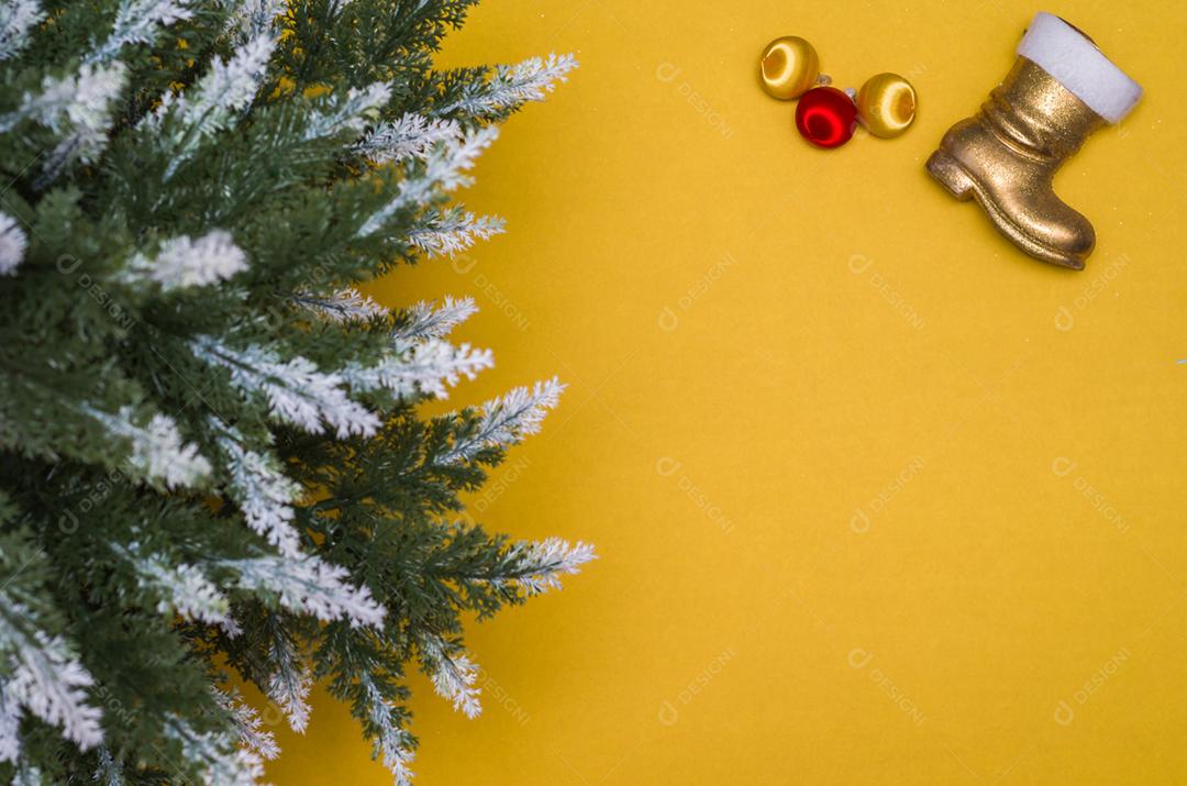 Textura com tema de Natal com folhas verdes, objetos decorativos e fundo amarelo.