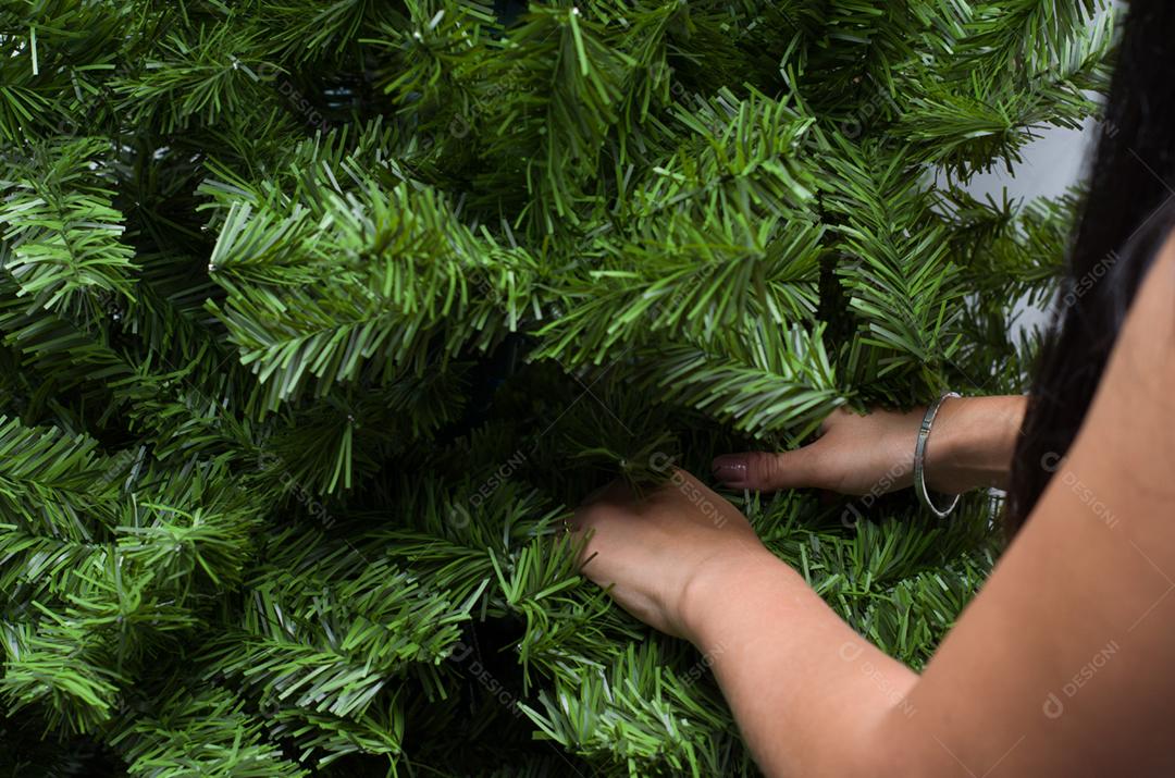 Mãos de mulher arrumando e decorando a árvore de natal