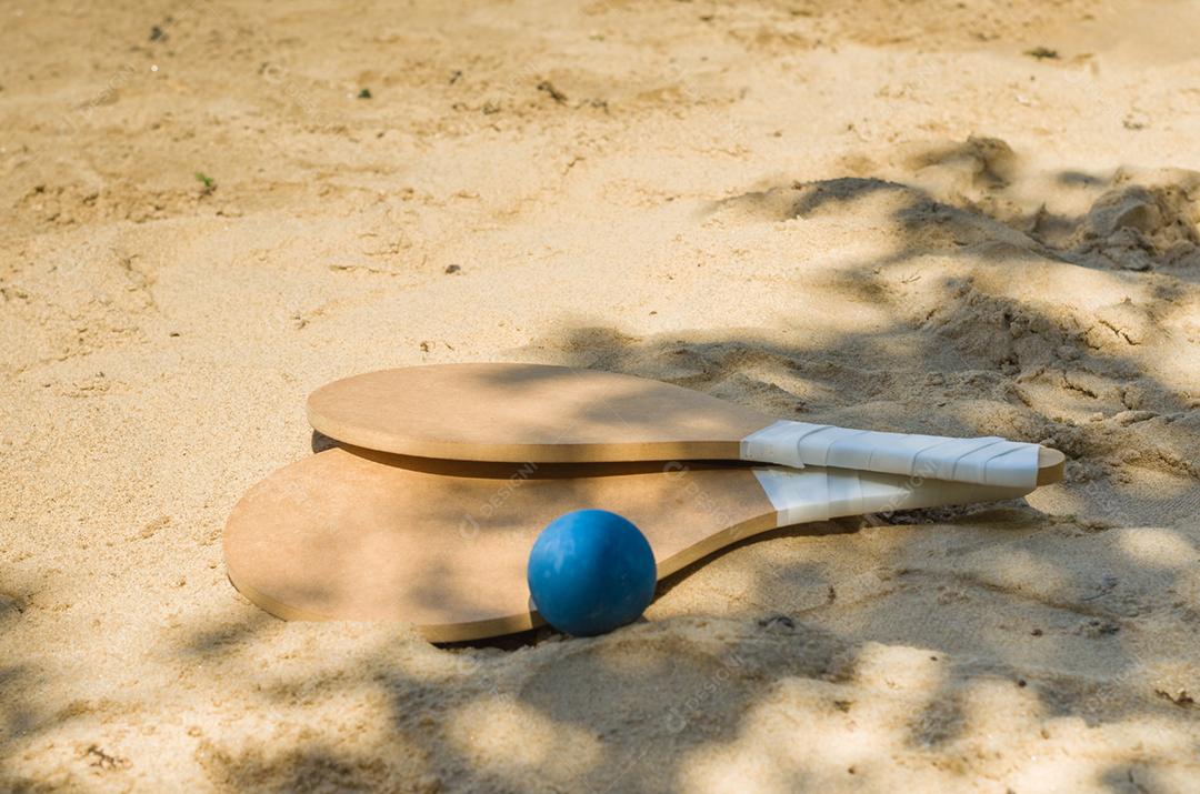 Raquetes de tênis de praia na areia, bebida caipirinha
