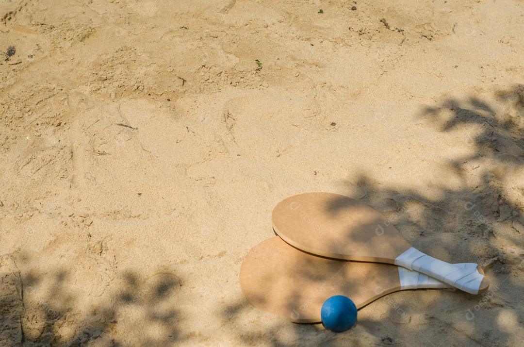 Raquetes de tênis de praia na areia, bebida caipirinha