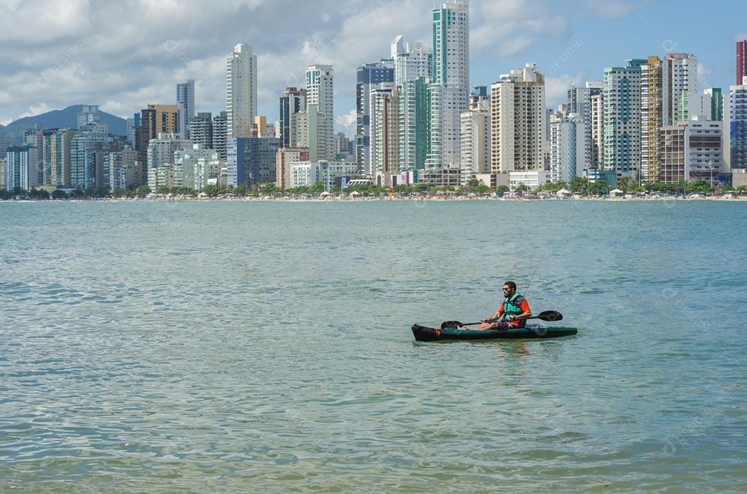 Jovem passeando de caiaque na praia brasileira. Caiaque de pesca.