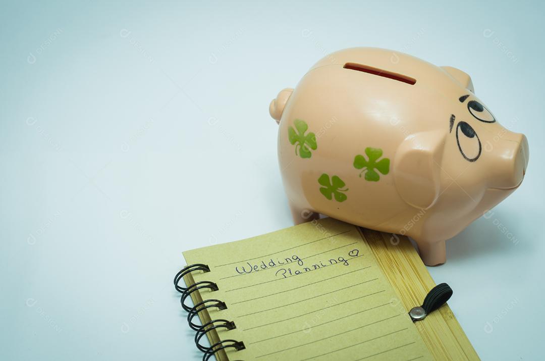 Grande conceito de economia para férias, cofrinho, caderno e caneta.