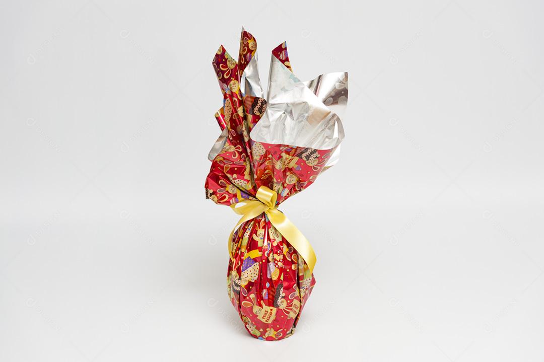 Ovo de Páscoa em linda embalagem vermelha com fita amarela. Imagem horizontal.