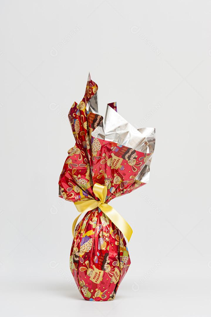 Ovo de Páscoa em linda embalagem vermelha com fita amarela. Imagem horizontal.