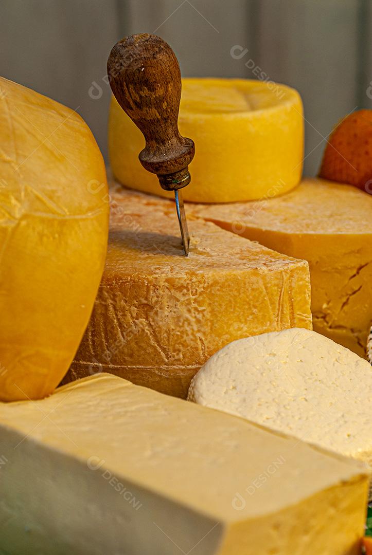 Diferentes tipos de queijos exibidos em uma mesa típica italiana, com cortadores especiais para cada tipo de queijo.