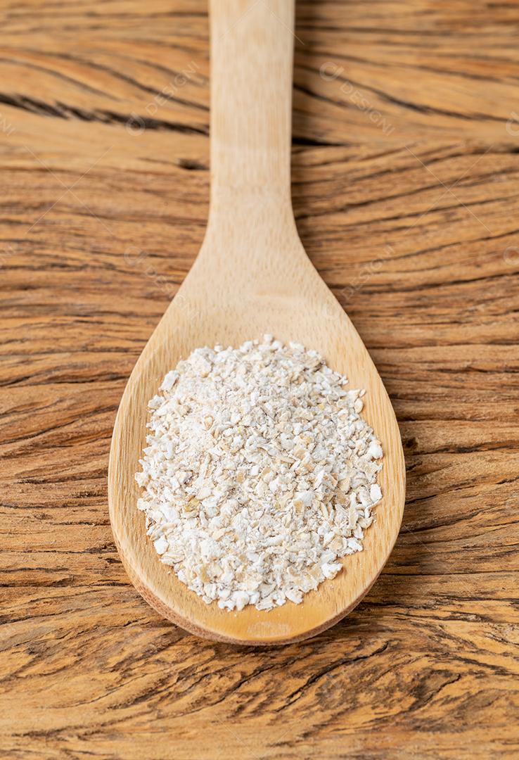 Farelo de aveia em uma colher sobre mesa de madeira