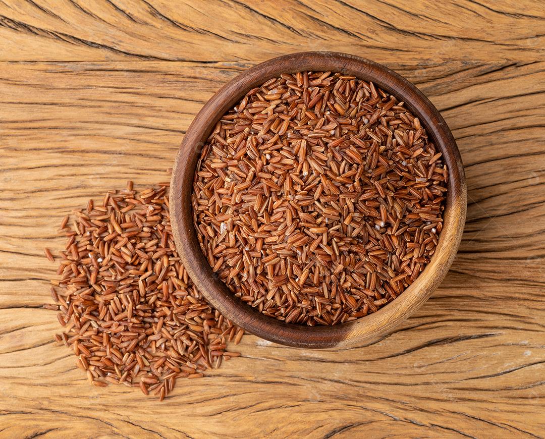 Arroz integral vermelho cru em uma tigela sobre mesa de madeira