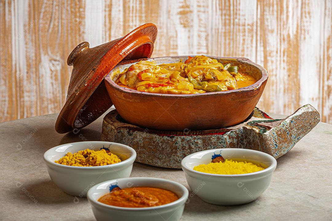 Moqueca de garoutureira servida com arroz de açafrão, farofa e pirão e molho de pimenta. Comida típica brasileira.