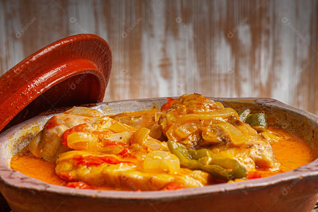 Moqueca de garoutureira servida com arroz de açafrão, farofa e pirão e molho de pimenta. Comida típica brasileira.