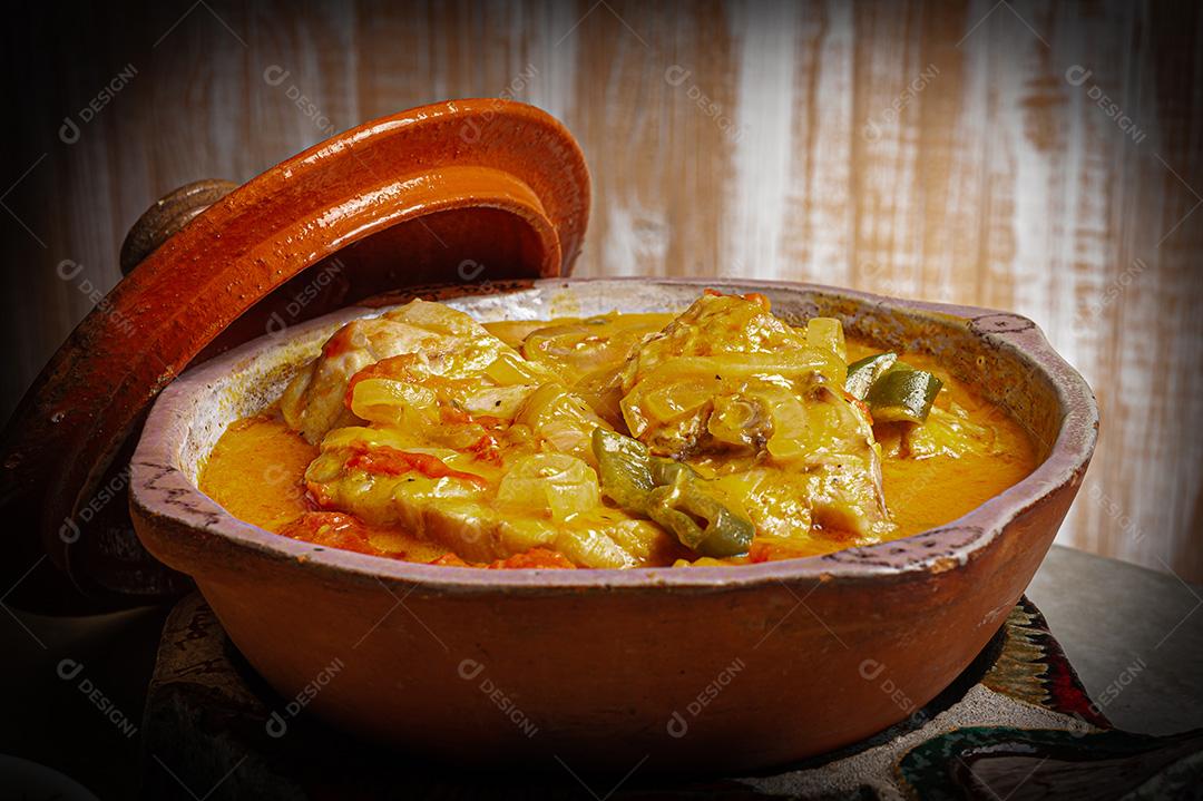 Moqueca de garoutureira servida com arroz de açafrão, farofa e pirão e molho de pimenta. Comida típica brasileira.