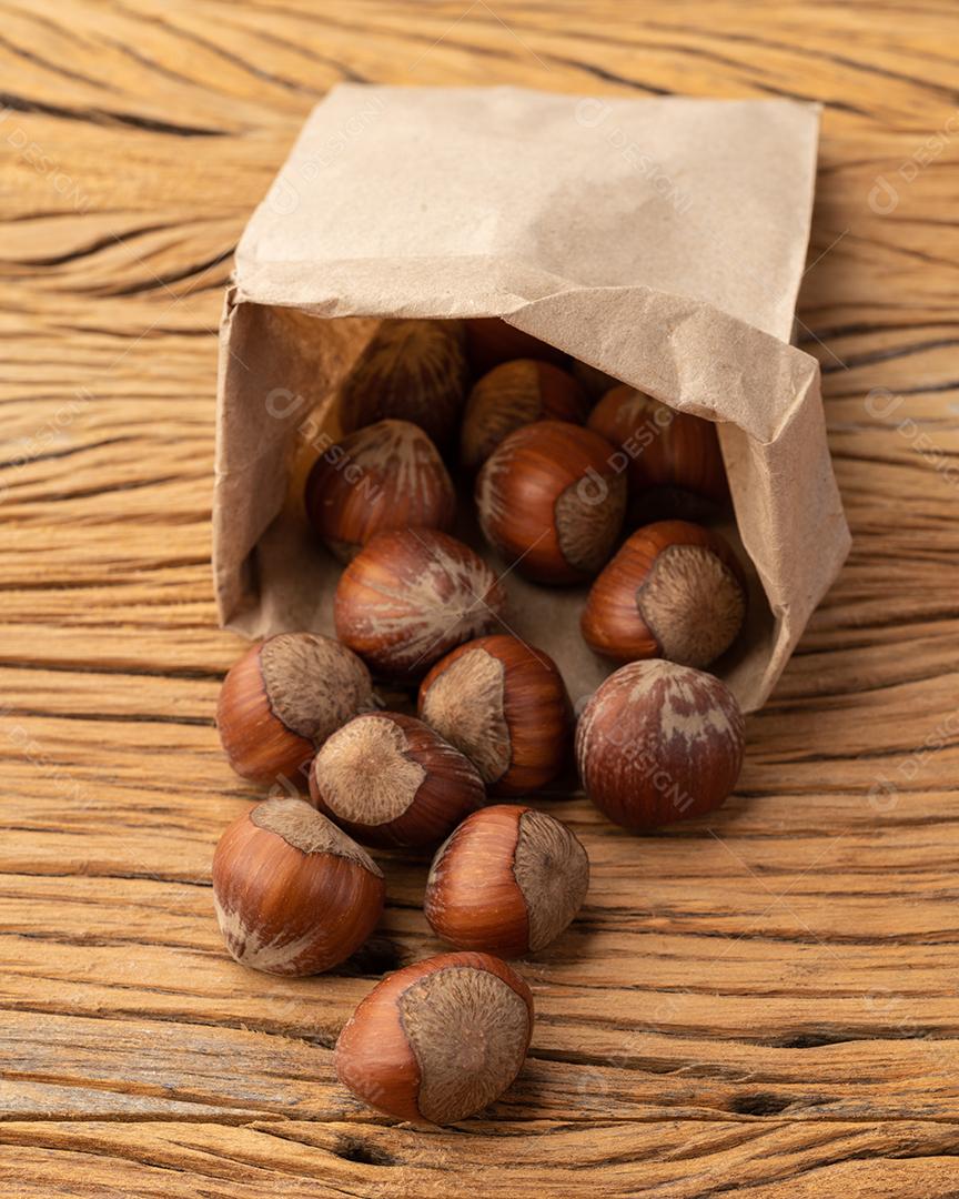 Avelãs em um saco de papel sobre a mesa de madeira.