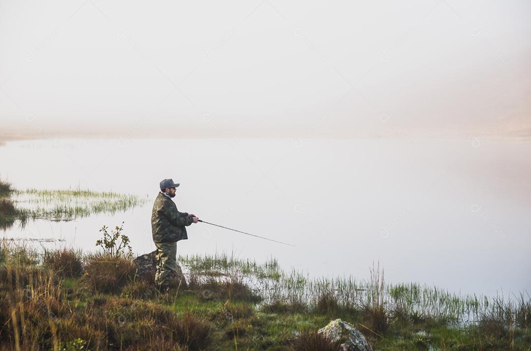 Pescador esportivo de pesca no lago em dia nublado