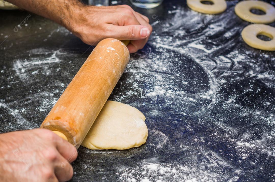 Preparando rosquinhas com rolo de macarrão em pedra.