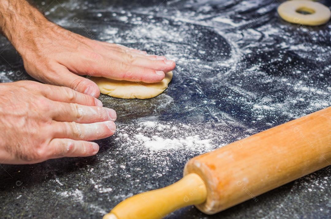 Preparando rosquinhas com rolo de macarrão em pedra.