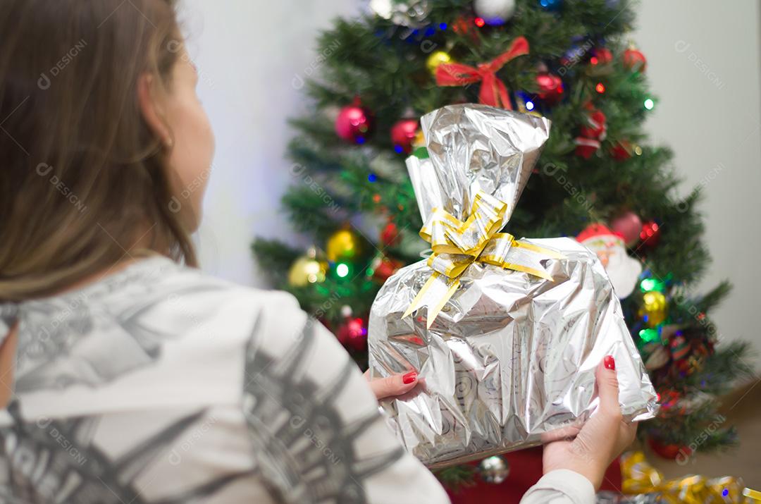Mulher abrindo presentes na árvore de Natal