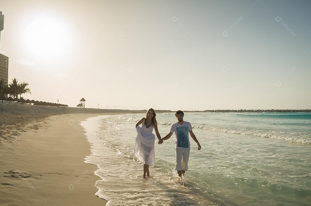 Casal de amantes andando de mãos dadas na praia do Caribe em sóis