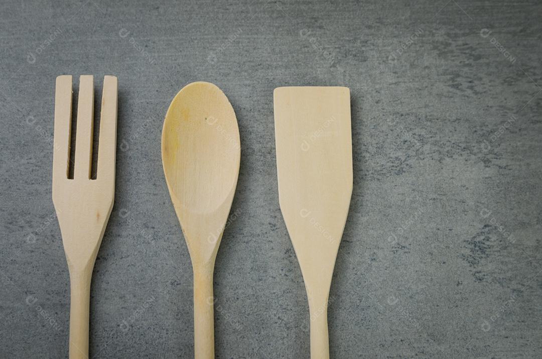 Talheres de madeira em fundo cinza.