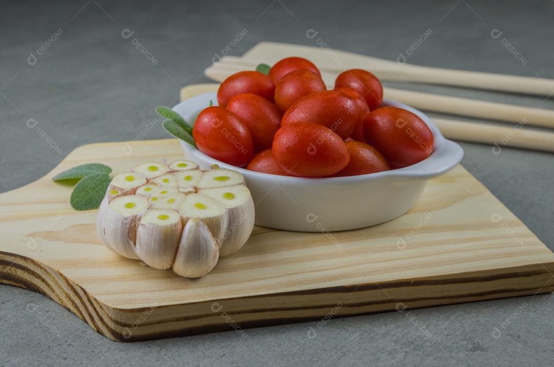 Placa de madeira com tomate cereja em fundo cinza. fundo culinário.