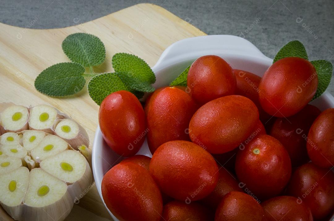 Placa de madeira com tomate cereja em fundo cinza. fundo culinário.