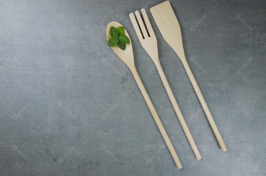 Talheres de madeira em fundo cinza.