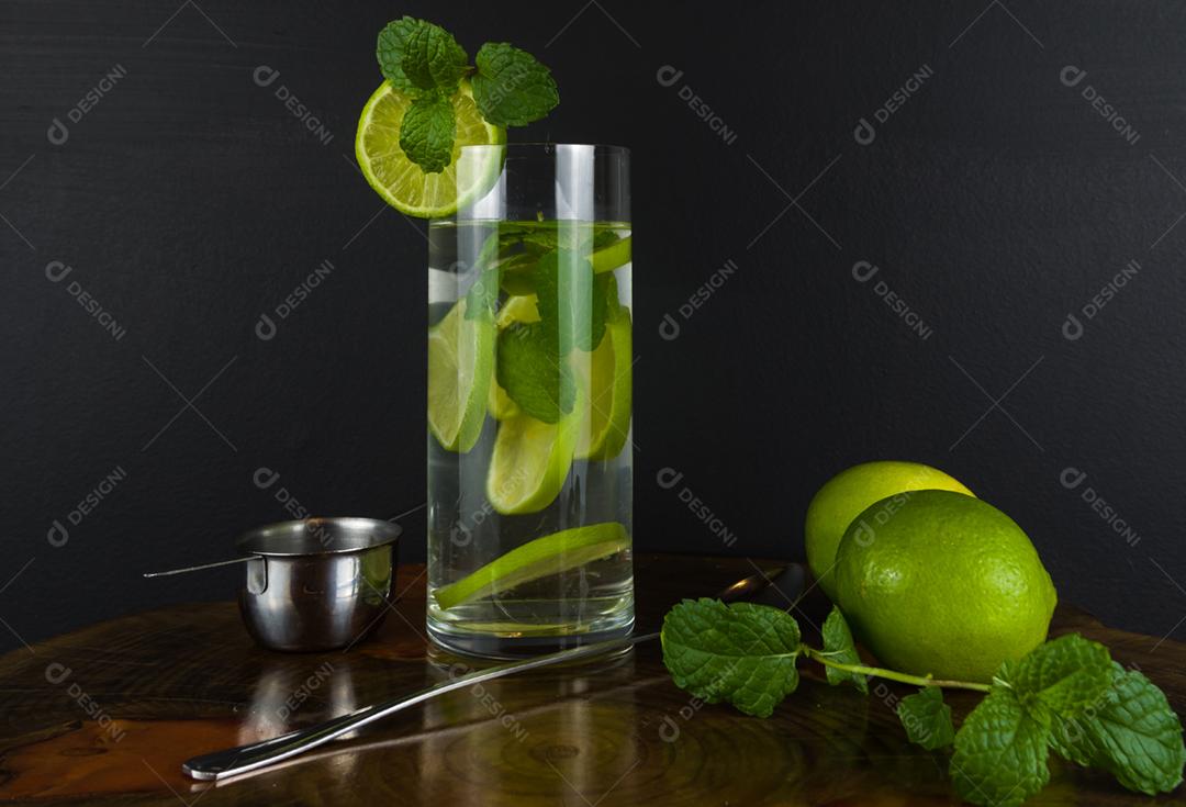 Copo de coquetel Mojito com hortelã e limão em uma placa preta com limões frescos. Água refrescante com gás
