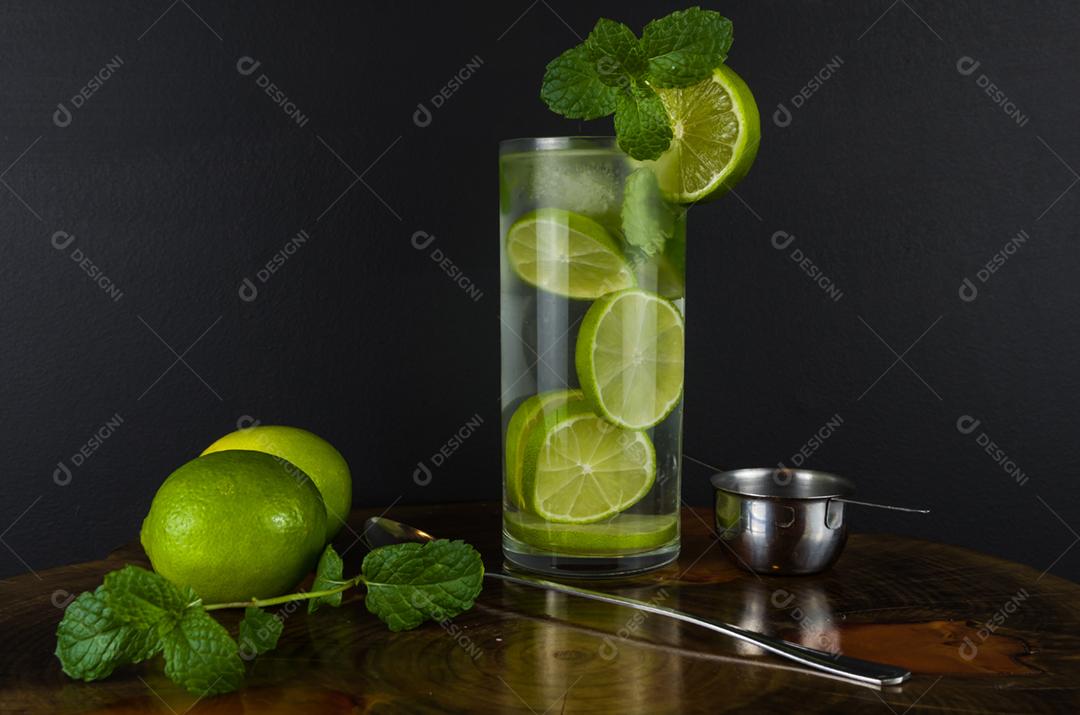 Copo de coquetel Mojito com hortelã e limão em uma placa preta com limões frescos. Água refrescante com gás