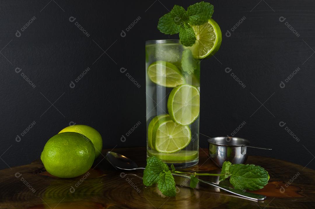 Copo de coquetel Mojito com hortelã e limão em uma placa preta com limões frescos. Água refrescante com gás