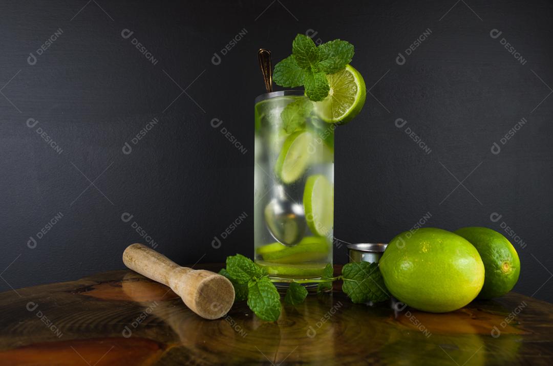 Copo de coquetel Mojito com hortelã e limão em uma placa preta com limões frescos. Água refrescante com gás