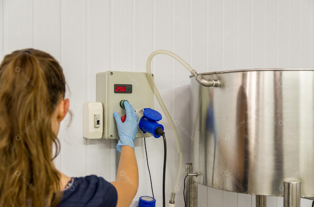 Mulher que trabalha na indústria, ajustando o termostato do tanque