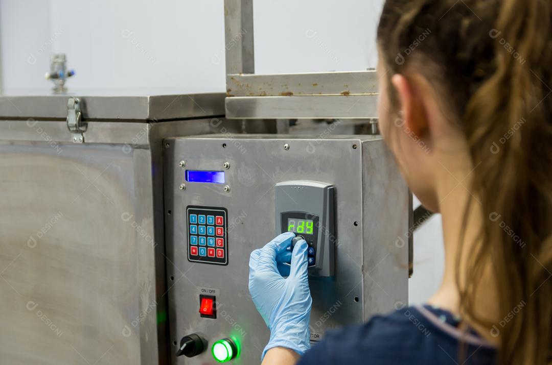 Mulher que trabalha na indústria, ajustando o termostato do tanque