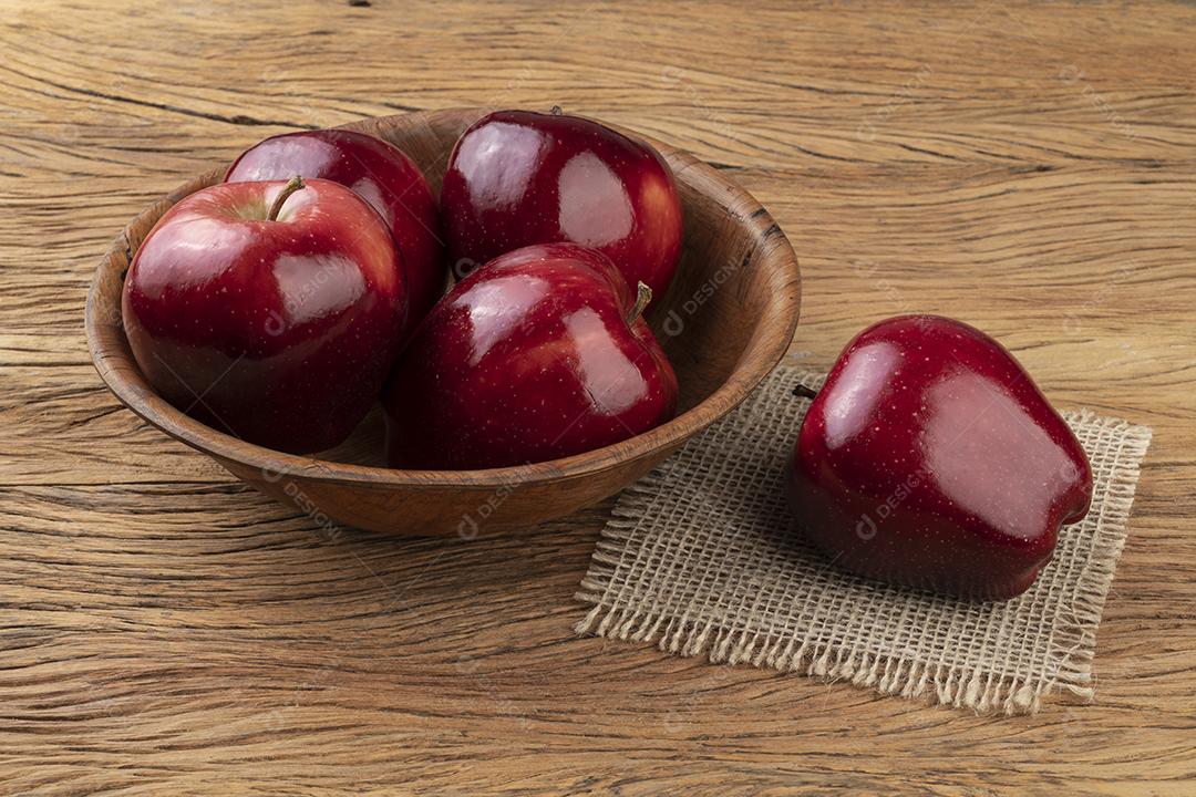 Maçãs vermelhas em uma tigela sobre mesa de madeira