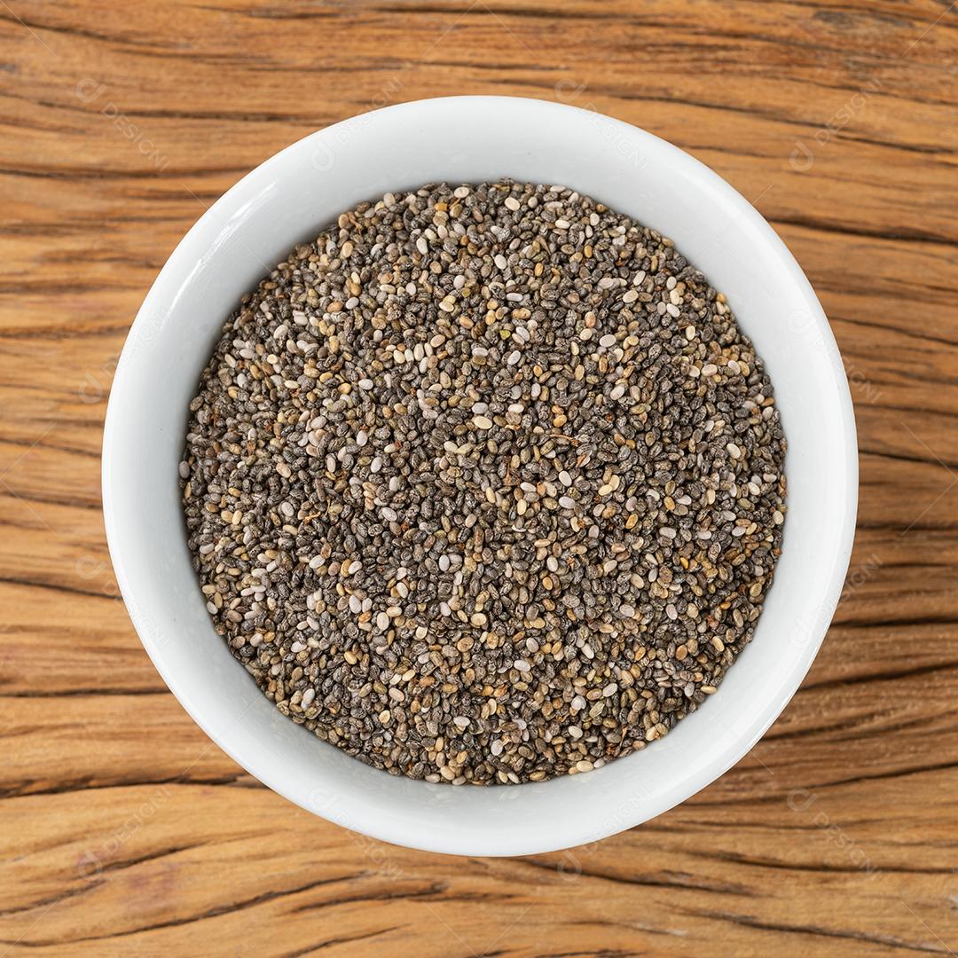Chia seeds in white bowl on wooden table
