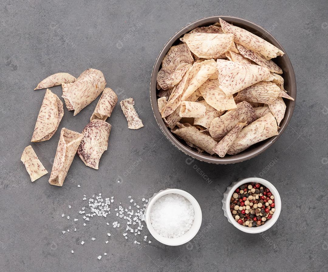 Inhame ou batatas fritas de taro em uma tigela com vegetais crus sobre pedra