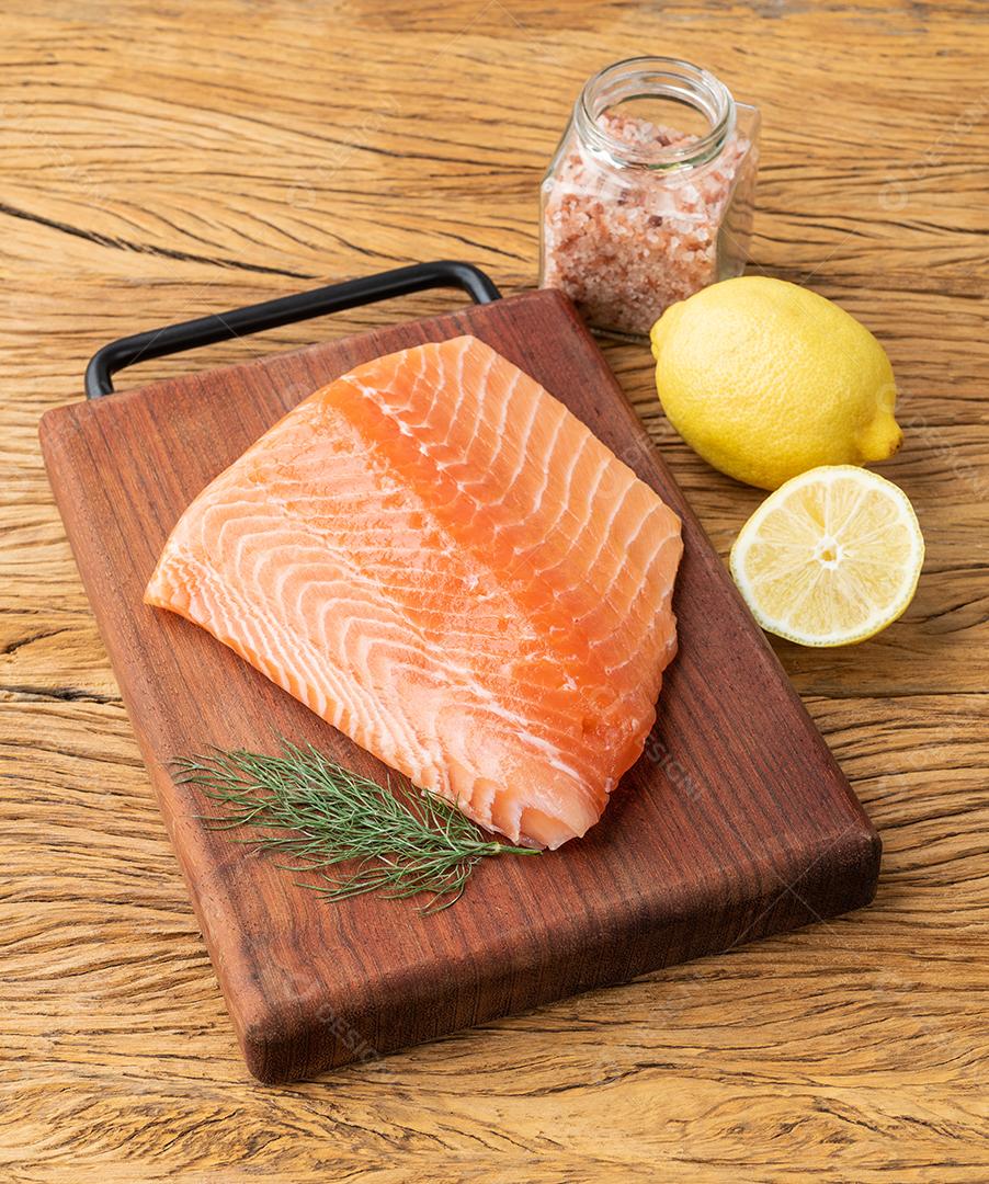 Filé de salmão cru com temperos sobre tábua de madeira