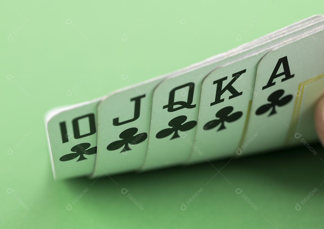 Mão mostrando royal flush sobre fundo verde