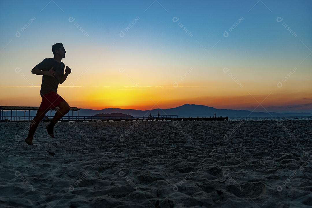 Homem jogando bola em praia com por do sol lindo. Esporte. Futebol