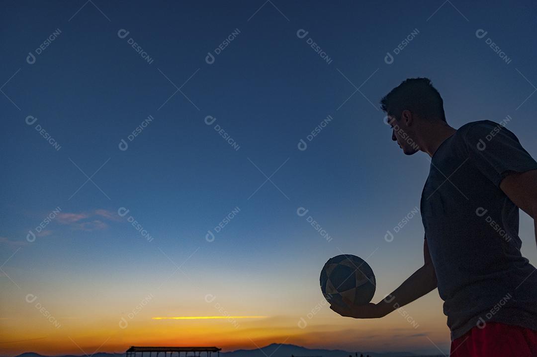 Homem jogando volei em praia no por do sol. Esporte.