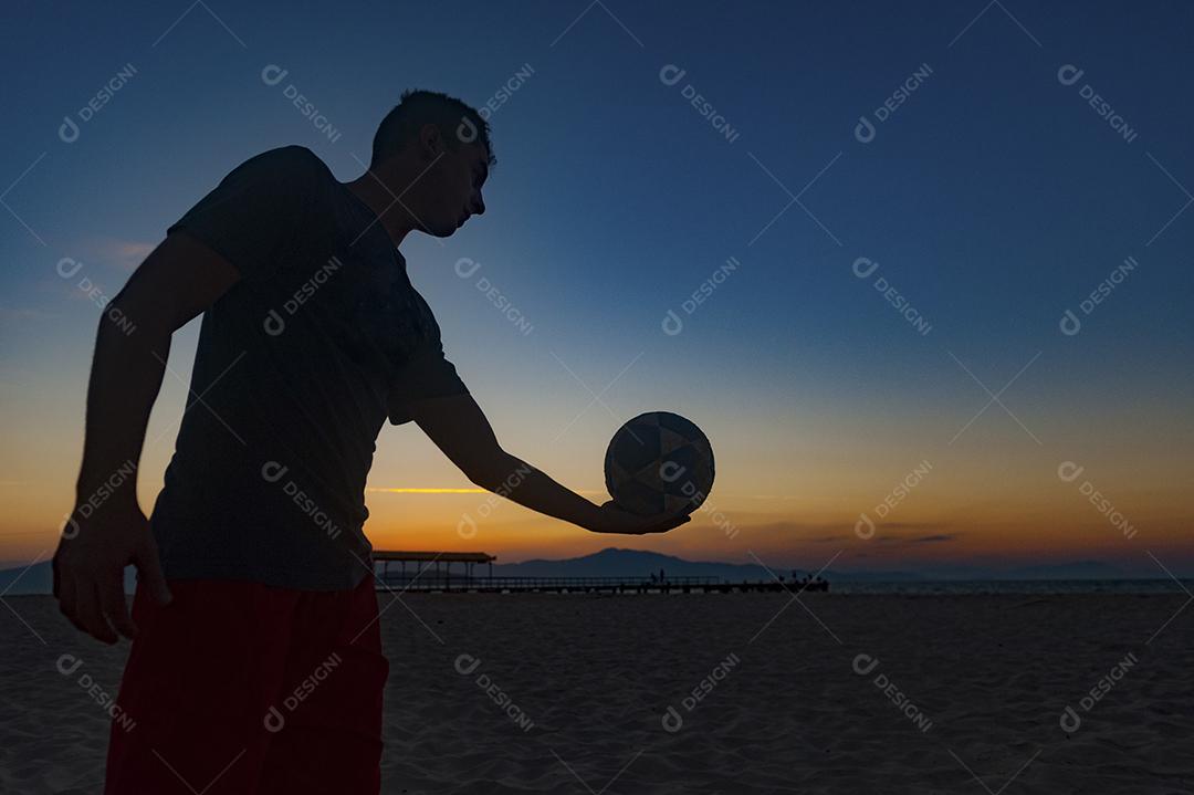 Homem jogando volei em praia no por do sol. Esporte.