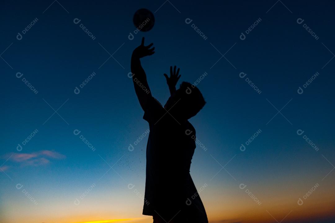 Homem jogando volei em praia no por do sol. Esporte.
