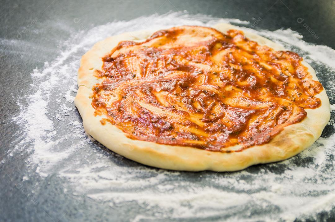 Preparando pizza, close-up de massa de pizza com molho de tomate.