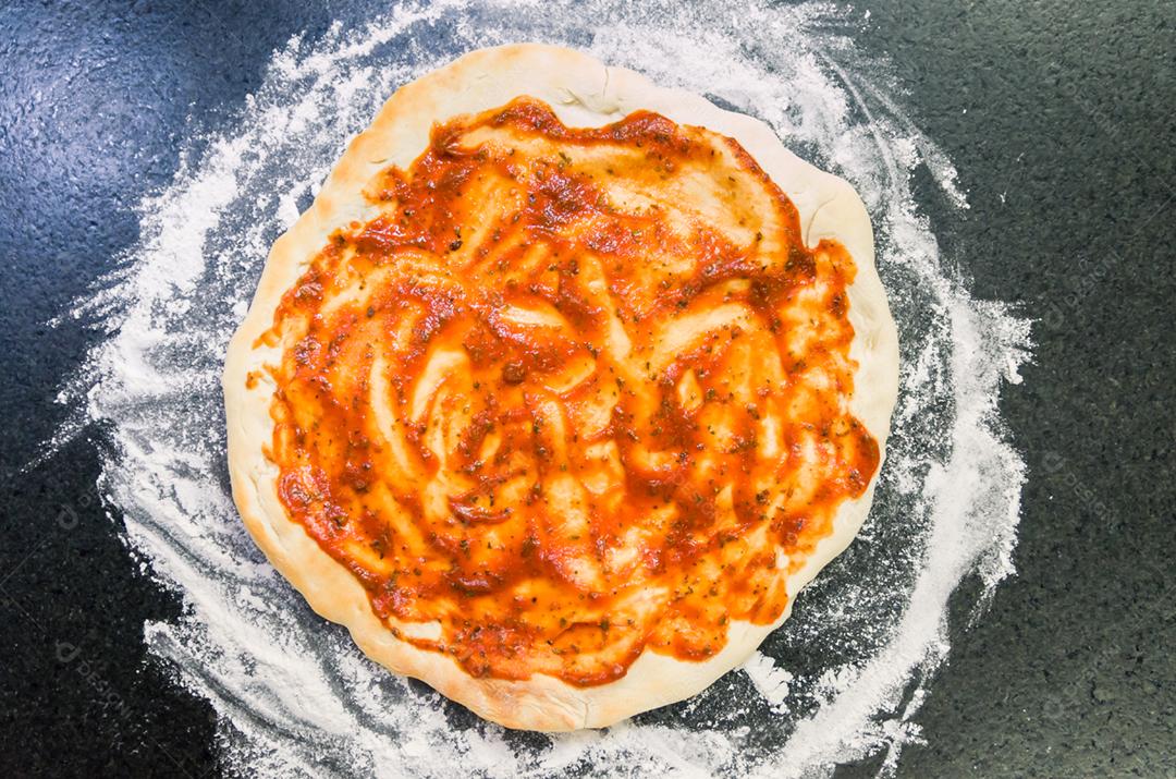 Preparando pizza, close-up de massa de pizza com molho de tomate.