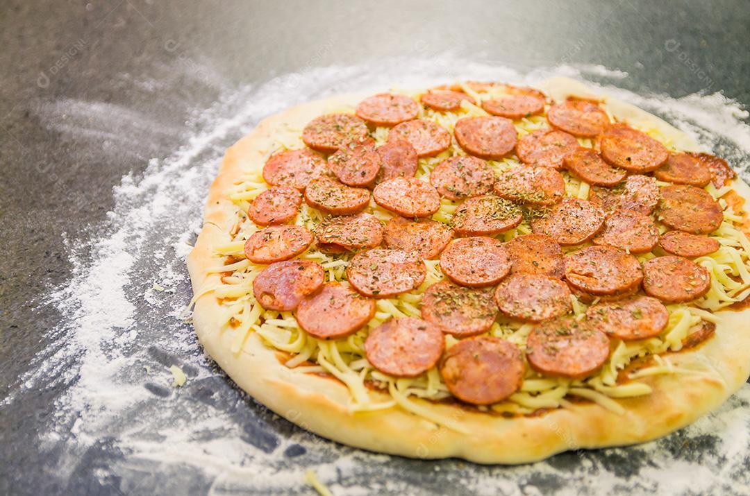 Preparando pizza de calabresa na mesa de granito preto