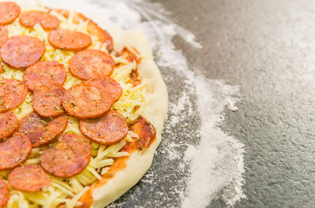 Preparando pizza de calabresa na mesa de granito preto