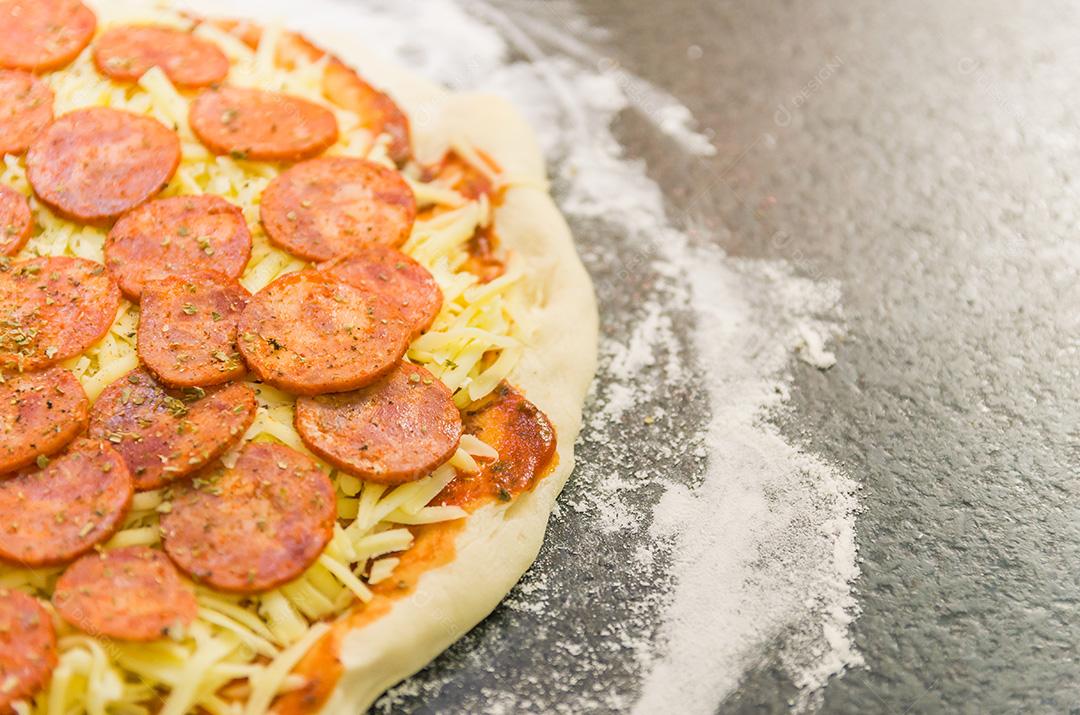 Preparando pizza de calabresa na mesa de granito preto