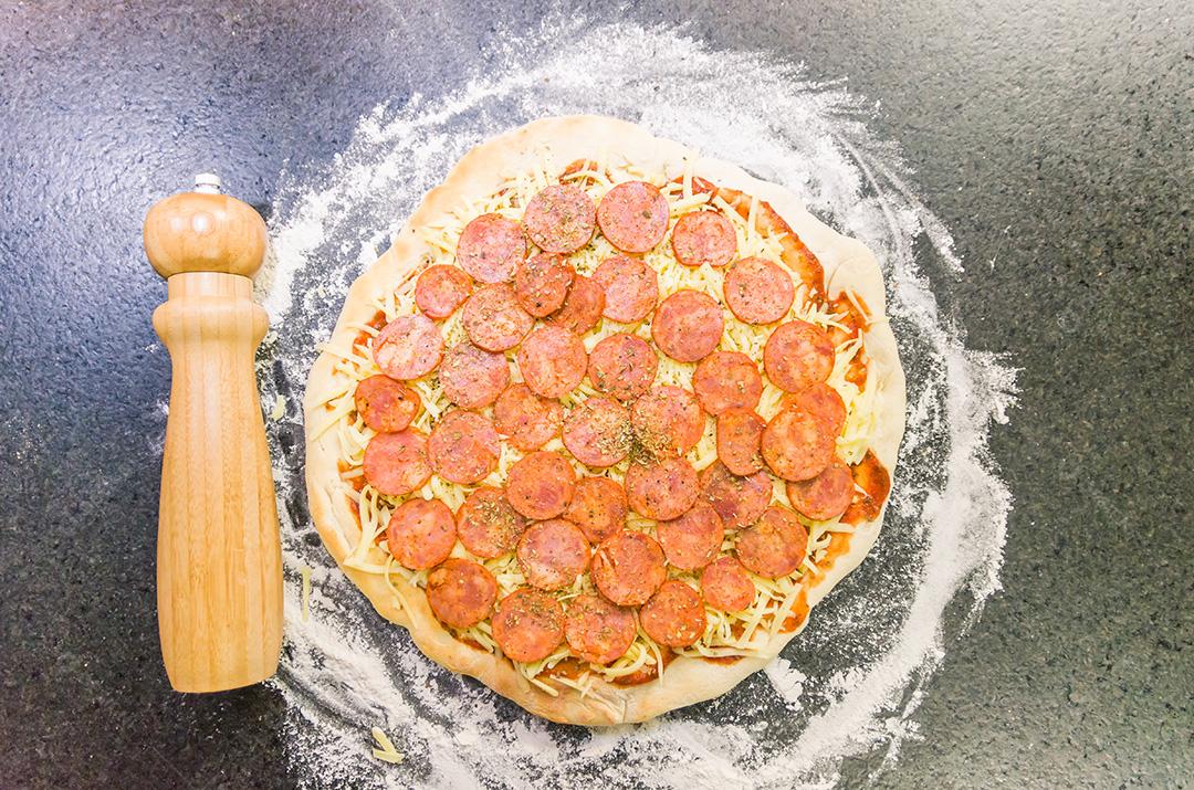 Preparando pizza de calabresa na mesa de granito preto