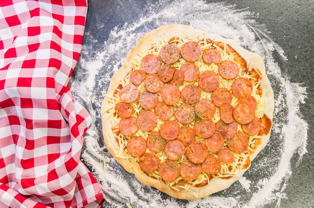 Preparando pizza de calabresa na mesa de granito preto