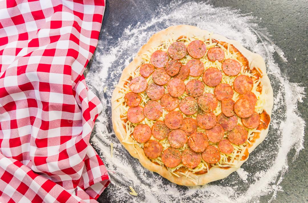 Preparing pepperoni pizza on the black granite table