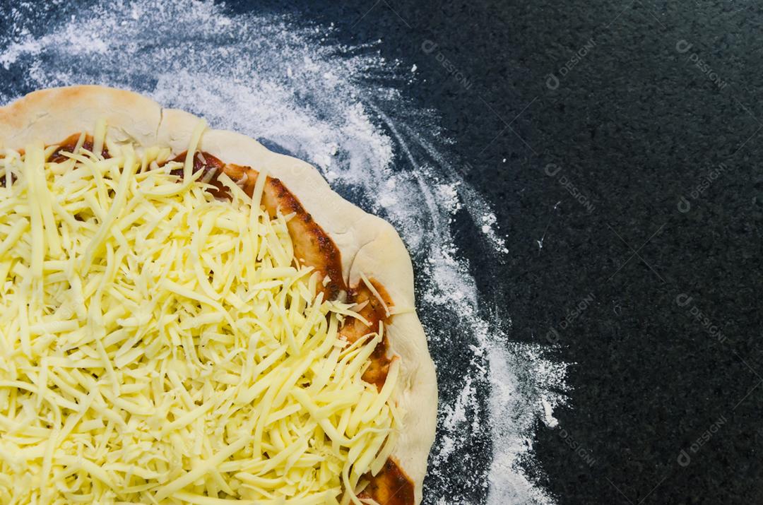 Preparando pizza, close-up de massa de pizza com molho de tomate e queijo mussarela.